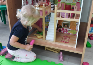 Dziewczynka bawi się domkiem dla lalek